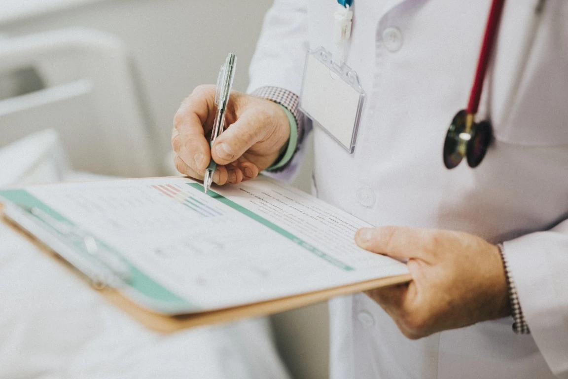 Médico preenchendo uma prancheta com papeis.